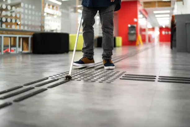 Visually impaired man using walking cane to walk at university