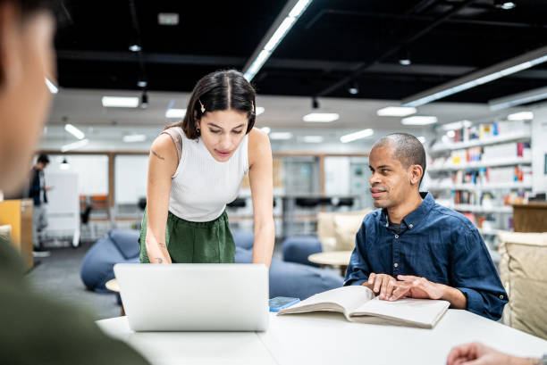 istock Young woman using a laptop while talk whit friend visually impaired at university 1453374333