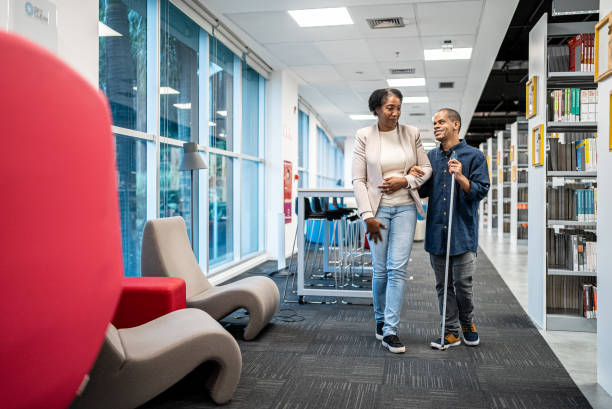 dojrzały nauczyciel towarzyszący osobom niedowidzącym na studiach - adult student women mature adult library zdjęcia i obrazy z banku zdjęć