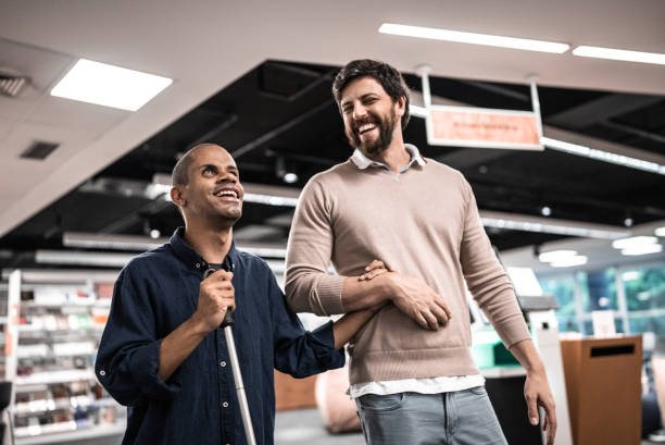 Mid adult man visually impaired talking with friend at university Mid adult man visually impaired talking with friend at university blindness stock pictures, royalty-free photos & images