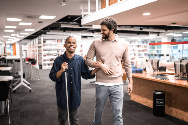 Mid adult man visually impaired talking with friend at university Mid adult man visually impaired talking with friend at university doing a favor stock pictures, royalty-free photos & images