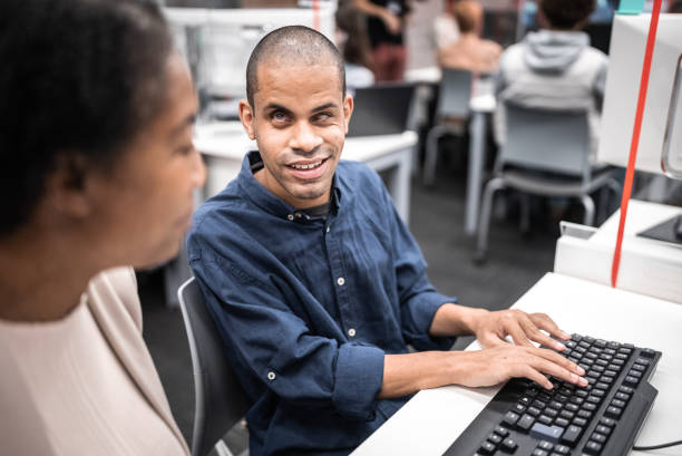 Mature woman support university student (or worker) with visually impaired to use computer at library