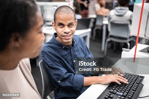 istock Mature woman support university student (or worker) with visually impaired to use computer at library 1453374411