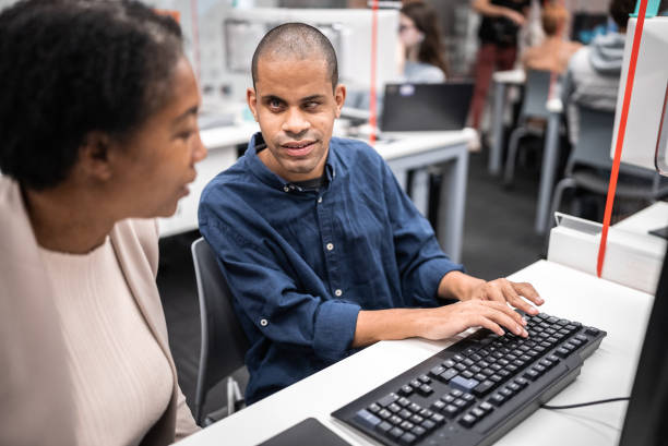 istock Mature woman support university student (or worker) with visually impaired to use computer at library 1453374419