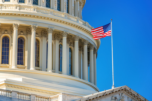 US Capitol and flag over blue sky, Washington DC