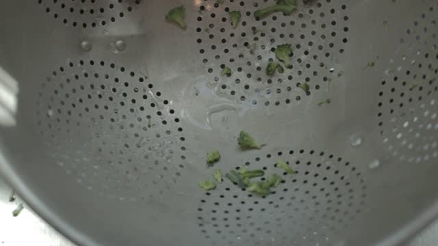 Colander with broccoli pieces in a sink