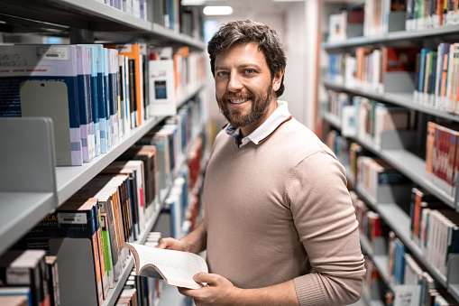 Portrait of a mid adult man reading a book at a library