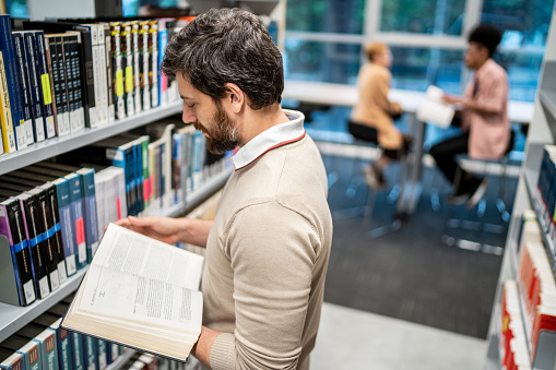 Mid adult man reading a book at a library