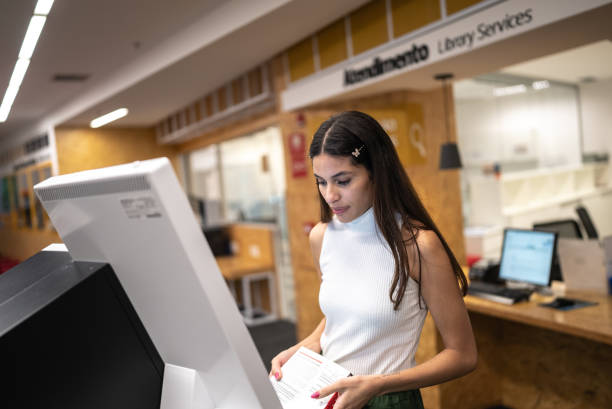 istock Young woman searching for a book in the library system at university 1453375385
