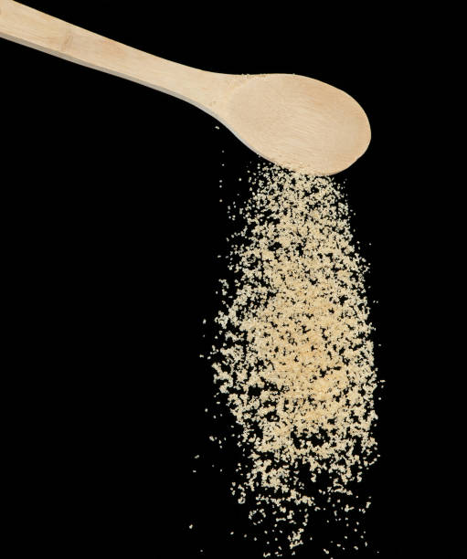 istock Brown Sugar fall, brown grain sugar pouring down abstract cloud fly from wooden spoon. Beautiful complete seed sugarcane, food object design. Selective focus freeze shot Black background isolated 1453375480