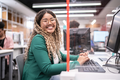 Portrait of university student working on computer in the library at campus