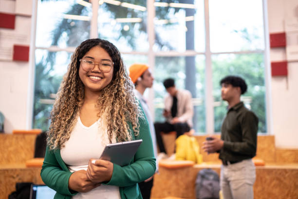 portrait of a young student woman holding a digital tablet at university auditorium - high school student imagens e fotografias de stock