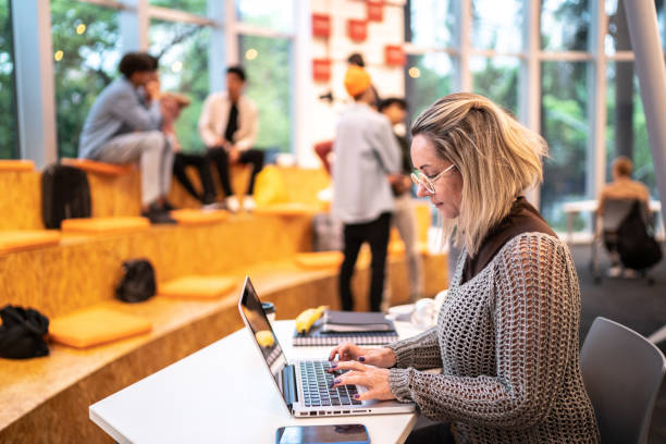 Mature woman using a laptop at university Mature woman using a laptop at university professor business classroom computer stock pictures, royalty-free photos & images