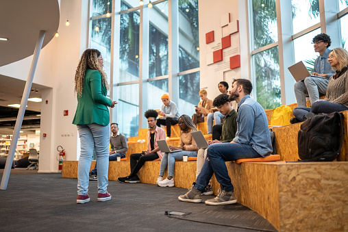 Young student woman giving lecture to students at the university