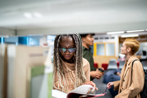 istock Young woman reading a book at university library 1453378267