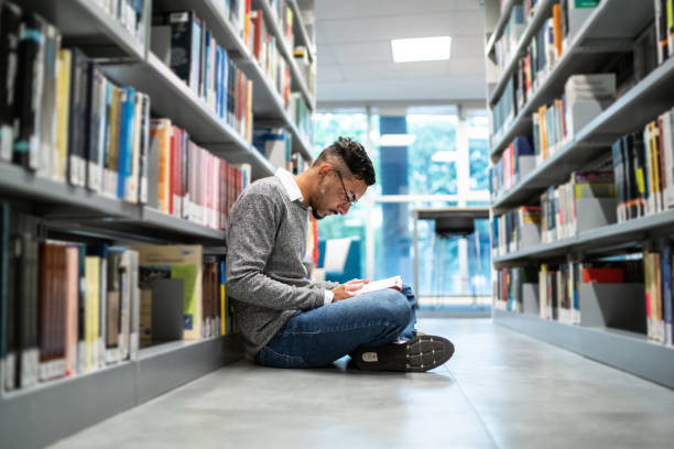istock Young student man sitting on ground at the university library 1453379926