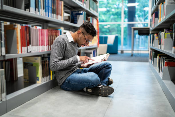 istock Young student man sitting on ground at the university library 1453379933