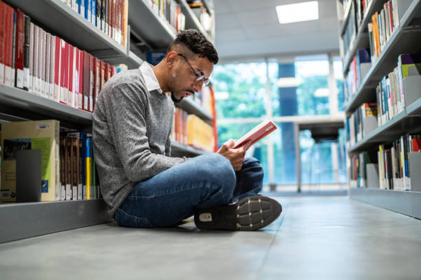 istock Young student man sitting on ground at the university library 1453379945
