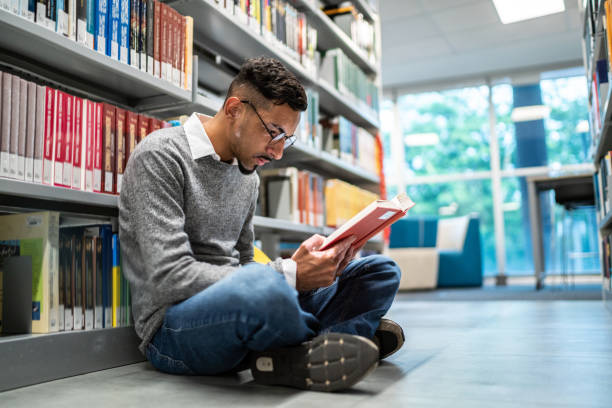 istock Young student man sitting on ground at the university library 1453380471