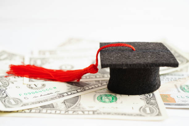 istock Graduation gap hat on US dollar banknotes money, Education study fee learning teach concept. 1453380672