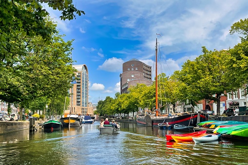 The Hague, Netherlands - June 19 2022: elegant boat in a typical canal with a vibrant blue sky, canoes and classic boat