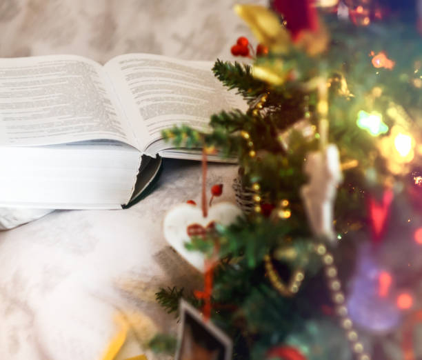 istock open thick book near christmas tree with lights 1453381816