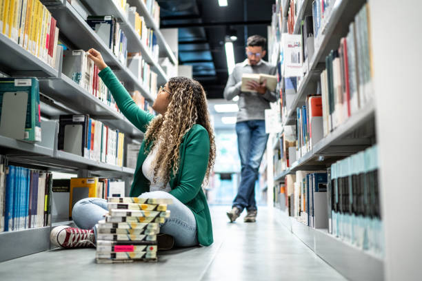 istock Young student woman choosing a book at university library 1453382837