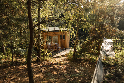 Small wooden cabin exterior in a glamping resort in the forest.