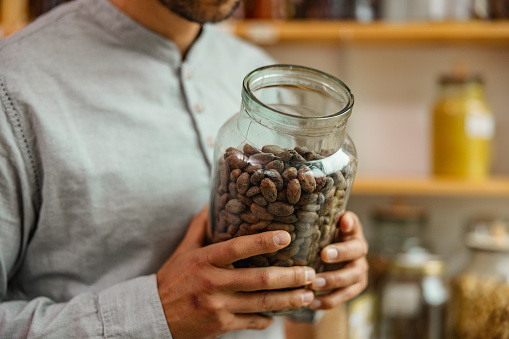 Close up of a male holding a reusable jar in a sustainable store.