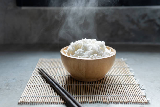 istock Cooked rice with steam in black bowl on dark background,hot cooked rice in bowl selective focus,hot food and healthy 1453388978