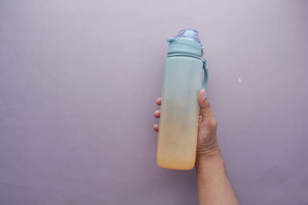 istock hand holding sport bottle on purple background 1453390980