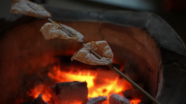 Street food in Thailand. Grill dried squid in a charcoal oven with bamboo sticks.