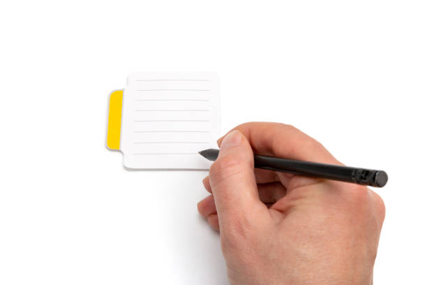 istock Hand with pencil writing on small lined sticky notes isolated on white background 1453393142
