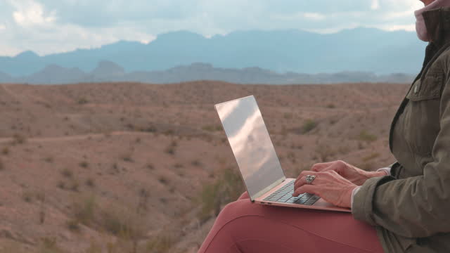 Mature woman uses laptop computer on ridge crest