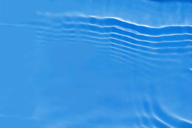 istock Defocus blurred transparent blue colored clear calm water surface texture with splashes and bubbles. Trendy abstract nature background. Water waves in sunlight with caustics. Blue water spay shinning 1453398507