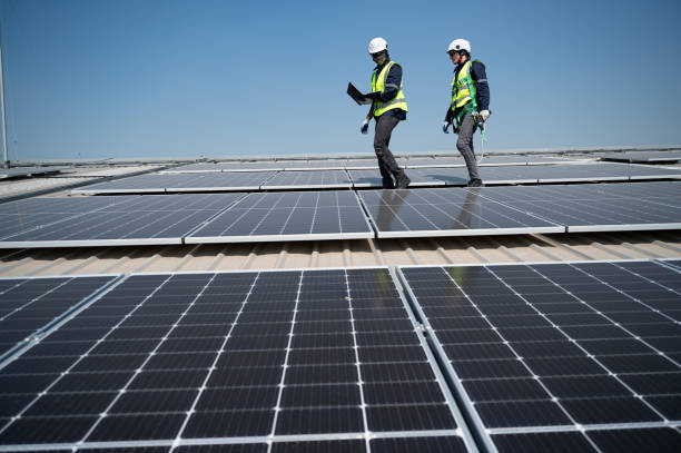 istock Caucasian and African American engineer man holding electric screwdriver and computer notebook walk and checking solar panel on roof factory 1453405633