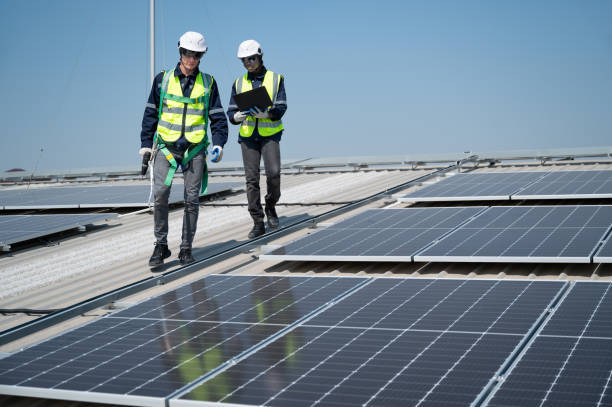 istock Caucasian and African American engineer man holding electric screwdriver and computer notebook walk and checking solar panel on roof factory 1453405638