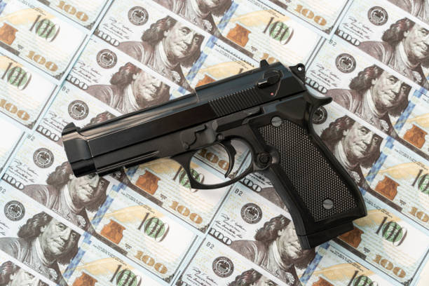 pistolet noir sur fond de dollars en espèces. le concept d’argent criminel ou de meurtre pour de l’argent. braquage - gun handgun violence kidnapping photos et images de collection