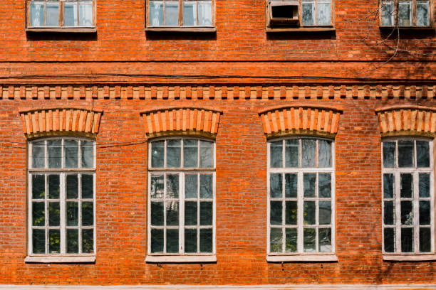 istock Old facade made from red bricks with huge white rounded vintage windows. Architect. Architecture. History. Heritage. Design. Grunge urban. Industrial style. Red brick wall 1453409022