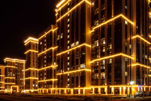 Night city. Modern residential multi-storey house with illumination. urban infrastructure. Glow-in-the-Dark Luxury Residential Complex Beautiful Background..