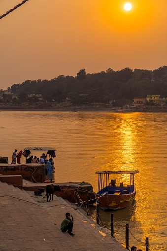 Rishikesh, India – October 18, 2022: A vertical shot of old boats on the Ganges river during dramatic sunset