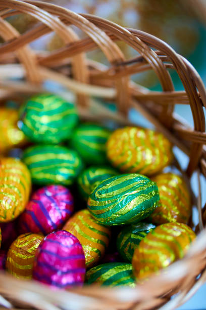 Easter Egg Basket filled to the Brim With eggs and chocolates for the Easter holiday, hand woven bamboo basket with stunning textures on a reflective surface with a perfect mirror image.