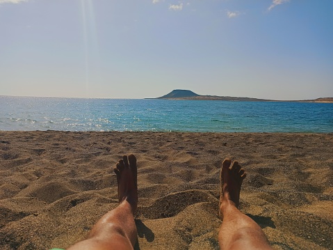 A view of a male's legs on the sand at the beach during daytime