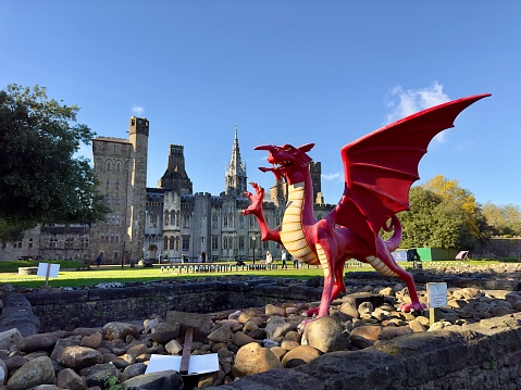 Cardiff, United Kingdom – November 04, 2022: A red dragon in front of the Cardiff Castle and Victorian Gothic revival mansion in Cardiff, Wales.