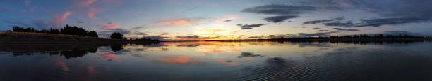 istock Panoramic shot of a calm lake with reflections against a scenic sunset 1453428556