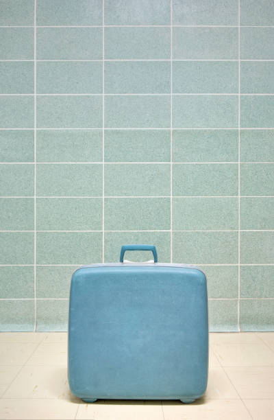 istock Blue vintage suitcase against a mid century modern tile wall, vertical 1453428864