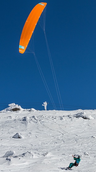 Sofia, Bulgaria – November 12, 2021: A vertical shot of a snowborder with snow kite against a blue sky
