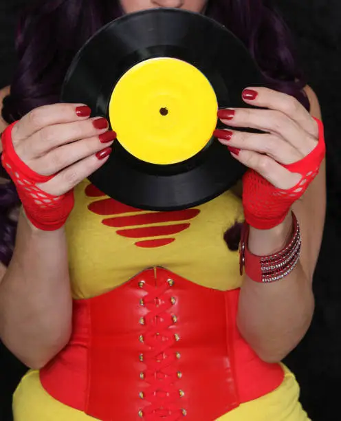 Woman in 1980s yellow clothing holding 45rpm record. Record label painted with yellow paint