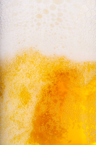 scatto verticale di birra e sfondo schiuma bianca - bitter beer bottle alcohol beer foto e immagini stock
