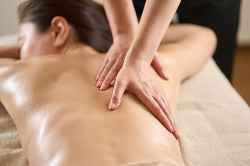 Woman receiving back massage at beauty salon